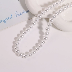 Détail de perles rondes blanches de 10mm sur un plateau pour la création de bijoux