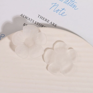 Macro detail of matte frosted resin flower charms with smooth edges and translucent white finish