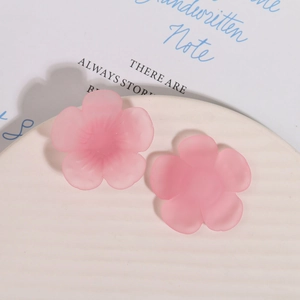Macro detail of matte pink resin flower accessories on a white ceramic tray