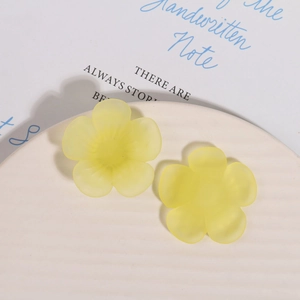 Macro view of matte yellow flower resin charms on a white textured ceramic dish