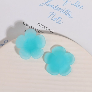 Detail of matte light blue resin flower charms with smooth frosted texture for DIY crafts