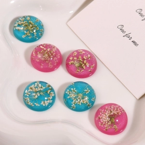 Macro detail of geometric resin charms with real dried flowers and glitter in white ceramic tray