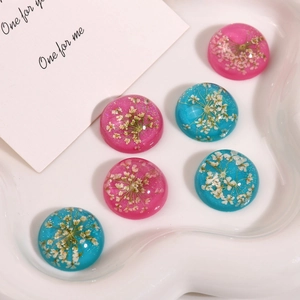 Macro detail of hemispherical resin beads with dried flowers and silver glitter on a tray