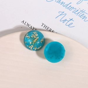 Macro shot of blue resin cabochons with dried flowers and glitter for DIY jewelry making