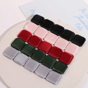Minimalist square satin fabric buttons in multiple colors displayed on a ceramic tray