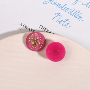 Macro shot of pink resin charms with embedded dried flowers and glitter for DIY earrings