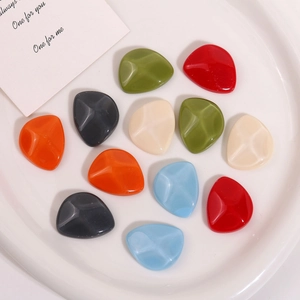 Close-up of colorful irregular resin charms for DIY jewelry making in a white ceramic dish