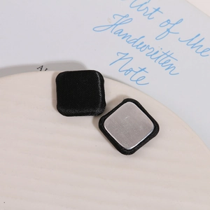 Detail of square black silk fabric buttons with polished silver metal backings