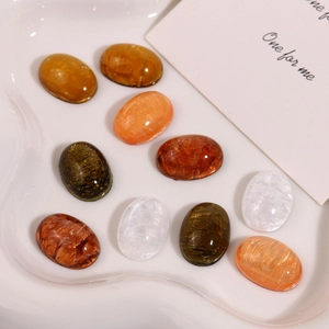 Macro detail of oval resin gemstones for DIY earrings on a textured white tray