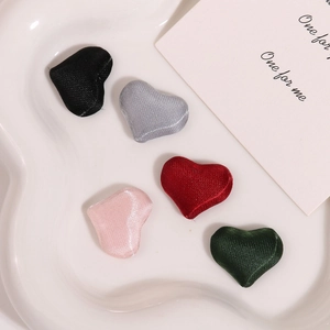 Detail of five heart-shaped fabric patches in mixed colors on a white ceramic tray