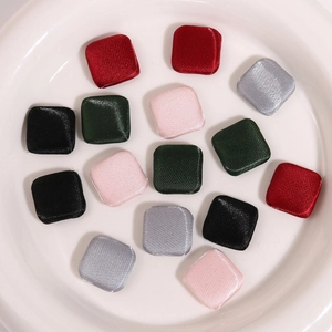 Flat lay of square satin fabric buttons in red, green, black, pink and silver colors
