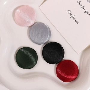 Gros plan de boutons recouverts de tissu satiné en cinq couleurs sur une assiette