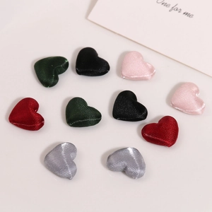 Macro detail of heart-shaped satin fabric buttons in multiple colors for DIY accessories