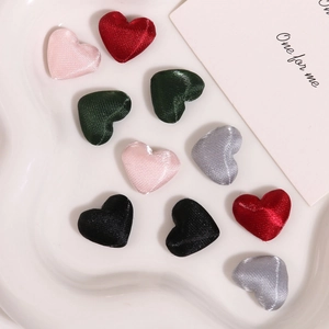 Macro shot of assorted satin heart fabric buttons in various colors on a white tray