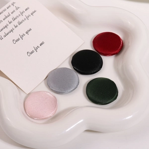 Gros plan de cinq boutons décoratifs en satin coloré sur un plateau en céramique