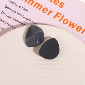 Macro shot of dark grey irregular resin charms for DIY earrings on a ceramic plate