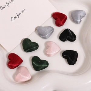 Flat lay of colorful satin heart-shaped fabric patches in a white ceramic tray