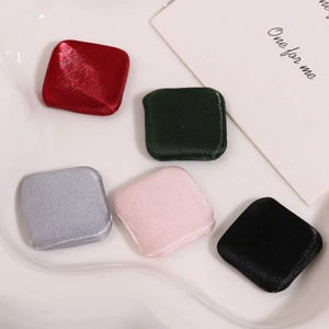 Detail of square satin fabric covered buttons in various colors on a white ceramic tray