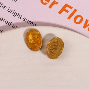 Macro shot of oval amber resin DIY charms with gold sand texture on a ceramic plate