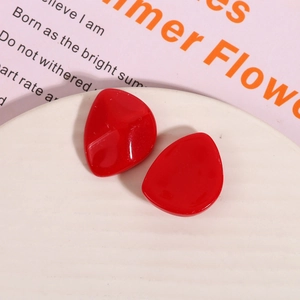 Macro shot of glossy red resin stud earrings with irregular geometric water drop shape
