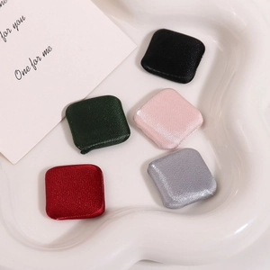 Square fabric covered buttons in various colors on a white tray for DIY sewing