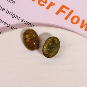 Macro shot of oval amber-toned resin cabochons with gold foil texture for DIY jewelry