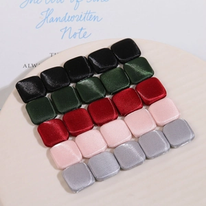 Square fabric covered buttons in five metallic satin colors displayed on a ceramic tray