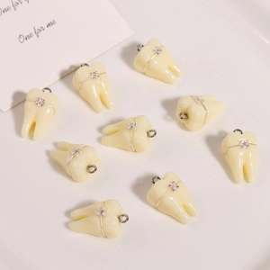 Dettaglio dei ciondoli a dente in resina con apparecchio metallico e anelli argento
