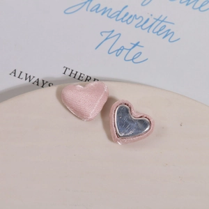 Detail showing pink satin fabric heart buttons with metal base for DIY jewelry crafts