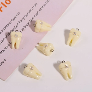 Dettaglio di ciondoli in resina a forma di dente con apparecchio in metallo per gioielli DIY