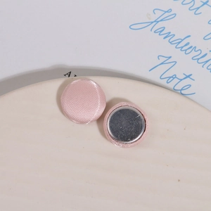 Dettaglio di bottoni magnetici in tessuto rosa a cuore su un piatto di ceramica