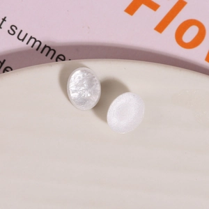 Macro shot of oval white resin charms with iridescent pearlescent finish for DIY jewelry