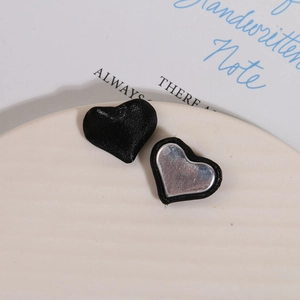 Detailed macro view of black silk and silver mirror heart buttons for DIY jewelry making