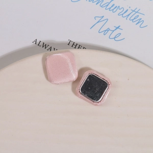 Macro detail of square fabric covered buttons with pink silk texture and metal backing