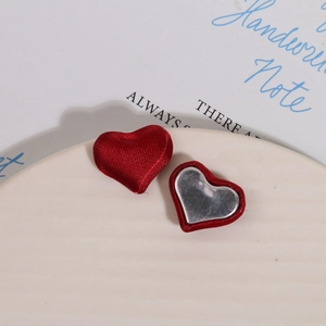 Detail of red and silver heart fabric charms on a white plate for DIY jewelry making