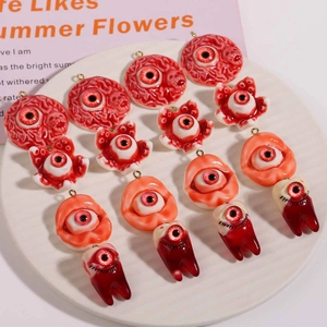 Creepy eye and teeth resin charms for Halloween necklace DIY, top view on white plate