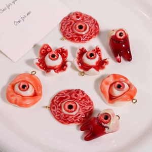 Macro detail of spooky resin eye and teeth charms with gold rings for DIY jewelry