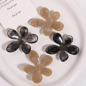 Detailed view of four resin flower hair clips in amber and smoke marble textures