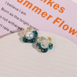 Detail von Harzblumen-Ohrring mit blauen Trockenblumen, Goldfolie und einer Perle