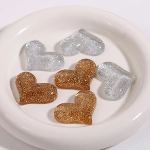 Close-up of glitter heart resin charms in gold and silver for DIY accessories