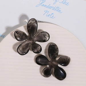 Detailed view of two grey marble ink pattern resin flower charms on a white textured tray