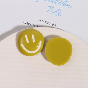 Macro view of mustard yellow resin smile face accessories on a decorative tray