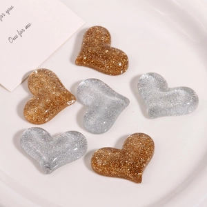 Macro shot of glitter heart resin charms in gold and silver for DIY accessories