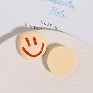 Detailed view of yellow resin charms with smiley face pattern on textured plate