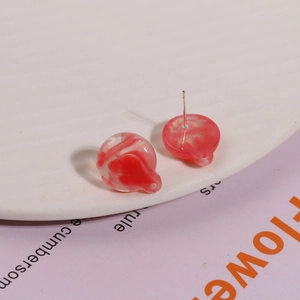 Macro view of round red marble resin earrings with silver pins on a ceramic plate