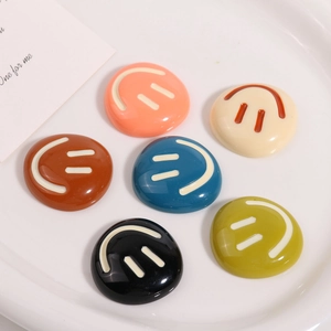 Set of six colorful smiley face resin charms in a white ceramic dish for DIY crafts