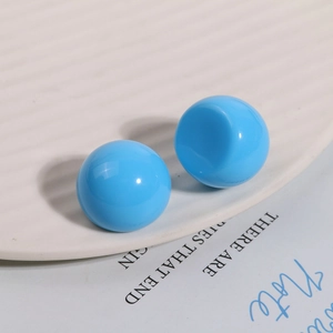 Close-up of bright blue glossy spherical resin beads on white ceramic tray for DIY jewelry