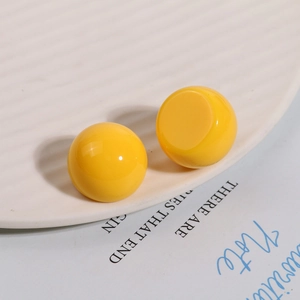 Close-up of bright yellow resin sphere charms on a ceramic plate for DIY jewelry making