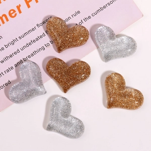 Close-up of heart-shaped glitter resin charms in gold and silver for DIY crafts