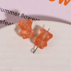 Macro view of translucent orange resin gummy bear charm with metal pin for DIY jewelry